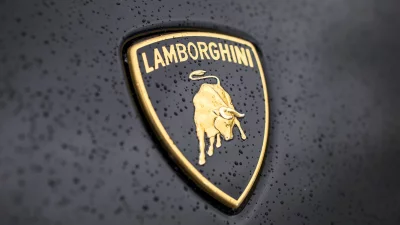 Iconic Golden Lamborghini Emblem on Wet Black Car Surface with Raindrops image