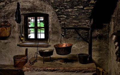 Rustic Stone Kitchen Hearth with Antique Copper Pots and Window View image