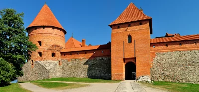 Historic Brick Castle Walls and Terracotta Roofs under Blue Sky image