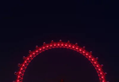 Iconic London Eye Ferris Wheel Glowing Red Against Night Sky image