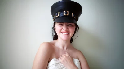 Joyful Young Woman in Stylish Black Cap and White Quilt Smiling Happily image