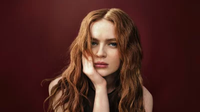 Portrait of a Pensive Young Woman with Red Hair, Freckles and Blue Eyes on Red Background image