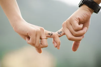 Romantic Couple's Pinky Promise Showcasing Commitment with Matching Anchor Tattoos and Engagement Ring image