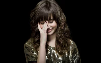 Glamorous Woman in Sparkling Sequin Top Laughing Coyly, Covering Her Face image