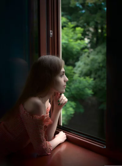 Thoughtful Young Woman Gazing Out Window, Pensive Reflection on Green Trees image