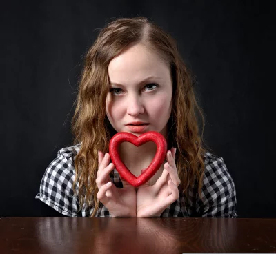 Young Woman with Intense Gaze Holding Red Heart Symbolizing Love and Affection image