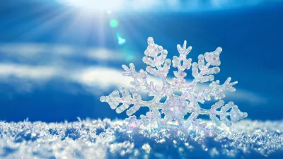 Sparkling Snowflake on Fresh Snow with Bright Sunlit Blue Sky Background for Winter Holidays image