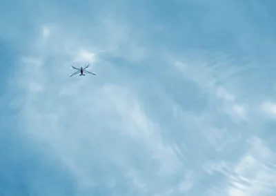 Minimalist lightweight drone flying in clear sky with soft clouds and reflection image