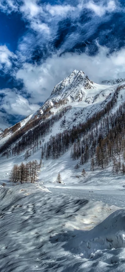 Majestic snow-capped mountain peak under a dramatic blue sky with clouds