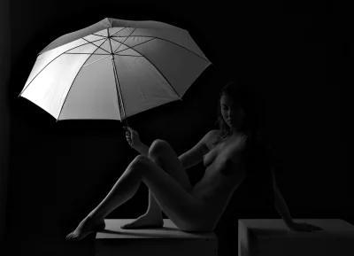 Nude Woman Posing Gracefully with White Umbrella in Dramatic Black and White Studio Light image