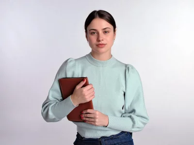 Young Woman in Green Sweater Holding Brown Tablet with Serious Expression image