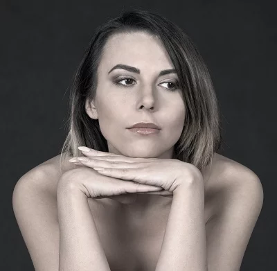 Pensive woman with expressive eyes resting chin on crossed hands monochrome portrait image