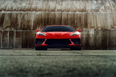 Stunning Red Sports Car Parked Against an Industrial Wall Cinematic Style Wallpaper image