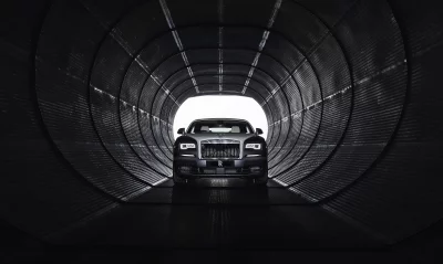 Sleek Black Rolls-Royce Luxury Car Emerging from Dramatic Dark Industrial Tunnel image