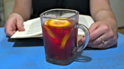 Woman's Hands Holding Open Book While Enjoying Warm Lemon Berry Tea image