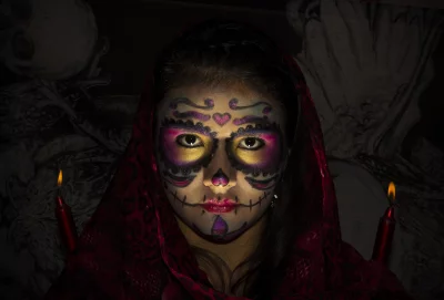 Festive Calavera Portrait: Woman with Traditional Sugar Skull Makeup and Glowing Candles image