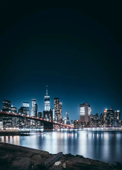 Iconic Brooklyn Bridge and Manhattan Skyline Reflecting on East River at Night image