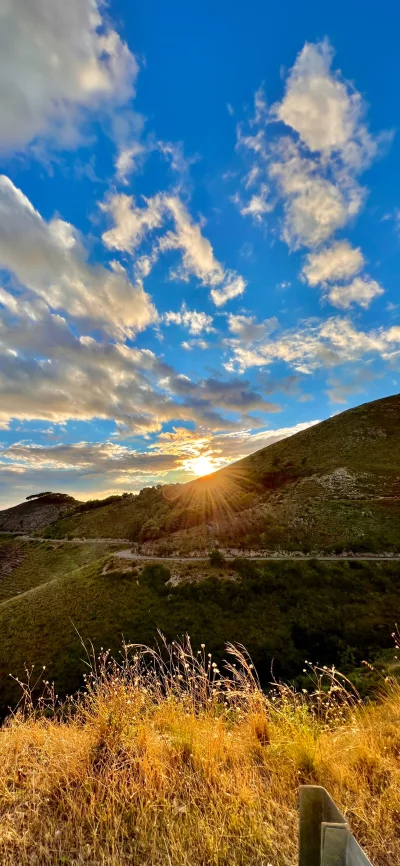 Radiant Sunset Over Rolling Hills with Winding Road and Golden Sunburst image