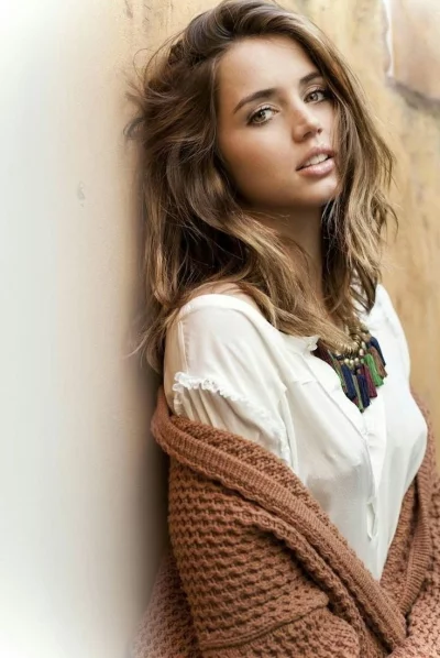 Beautiful Young Woman with Wavy Hair Leans Against Wall in Relaxed Pose Capturing Natural Allure image