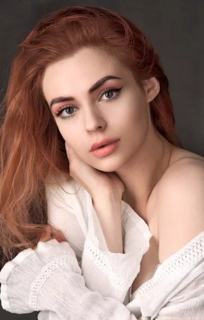 Young Redhead Woman Resting Chin on Hand, Pensive Gaze image