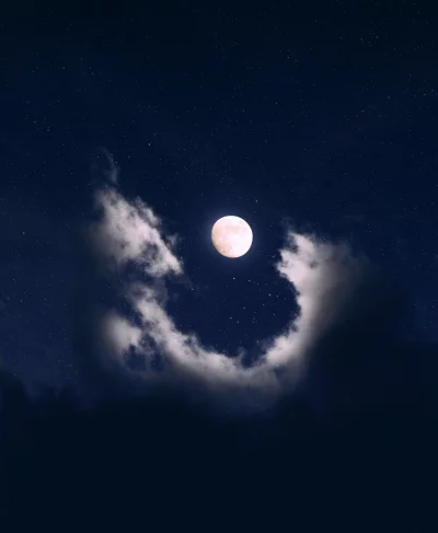 Ethereal Full Moon and Starry Sky Framed by Dark Clouds at Night image