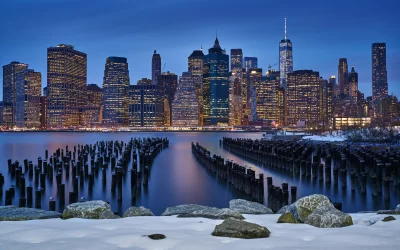 Stunning Manhattan Skyline at Dusk with Illuminated Buildings and Snowy Shoreline in Winter image