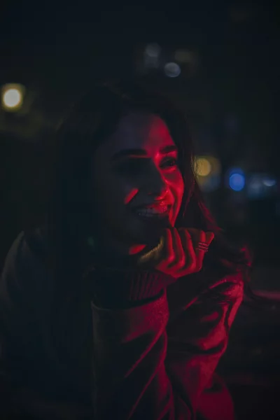 Enigmatic Woman Smiling in Vibrant Red Light with Bokeh Background