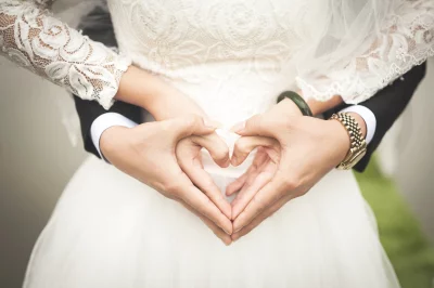Romantic Wedding Couple's Hands Form Heart Shape in White Dress and Black Suit image