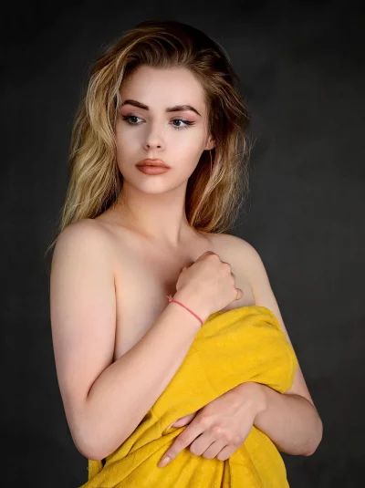Pensive Young Woman Draped in Yellow Towel with Wavy Blonde Hair image