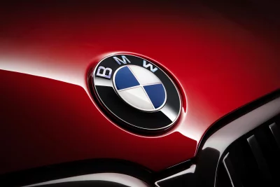Close-up of a classic BMW logo on the sleek red hood of a luxury automobile image