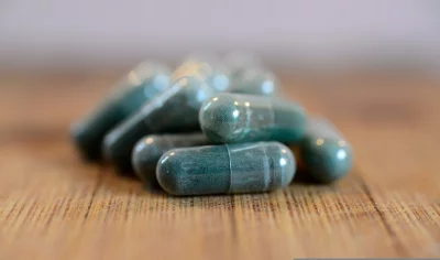 Natural Green Supplement Capsules on Wood: Health and Wellness Concept image