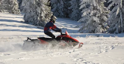 Dynamic Snowmobile Adventure in Sunlit Winter Forest Landscape image