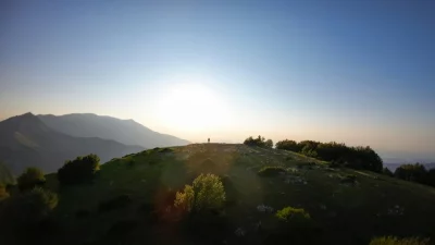Lone Hiker Silhouetted Against a Golden Sunset on a Mountain Peak