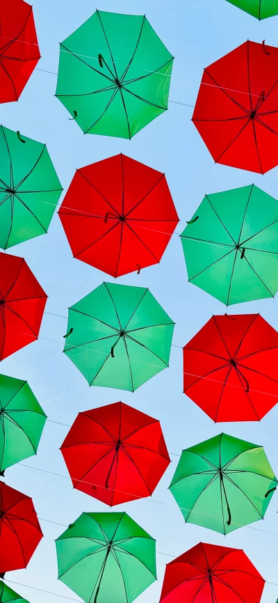 Vibrant Red and Green Umbrellas Floating Against a Clear Blue Sky Outdoor Decoration image