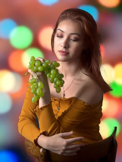 Young Woman Savoring Fresh Green Grapes Amidst Vibrant Bokeh Lights image