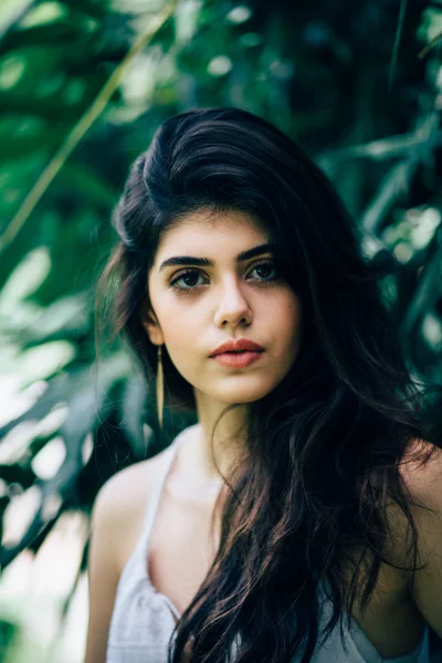 Beautiful Young Woman with Dark Hair Looking Directly at Camera in Natural Green Setting Stock Photo image