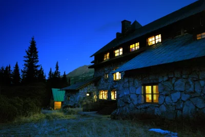 Cozy Mountain Lodge Illuminated at Dusk Amidst Pine Trees and Alpine Peaks image
