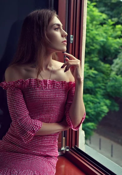 Pensive Woman in Off-Shoulder Gingham Dress Gazing Thoughtfully Out Window image