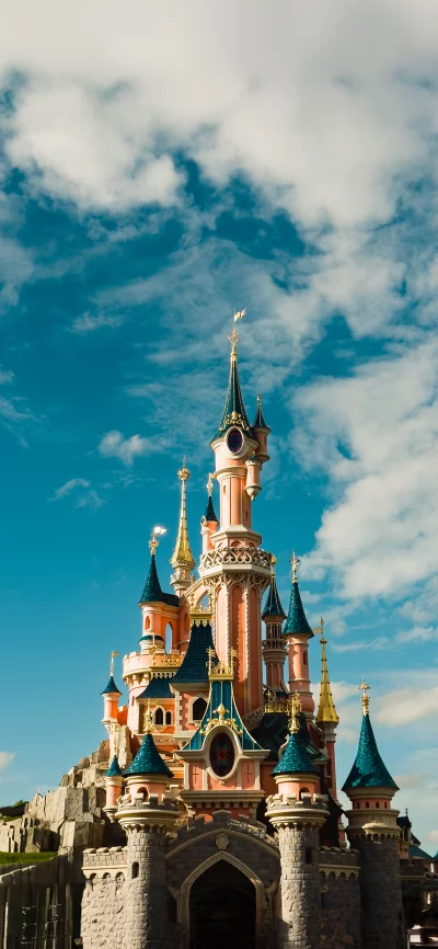 Majestic Fairytale Castle Against Dramatic Blue Sky with Fluffy White Clouds image