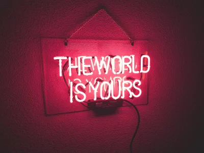 Inspiring Cinematic Pink Neon Sign Glowing The World Is Yours Quote Aesthetic Wallpaper image