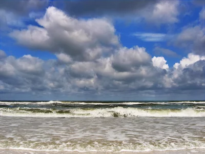 Dynamic Ocean Waves Crashing on Sandy Shore Under Dramatic Cloudscape image