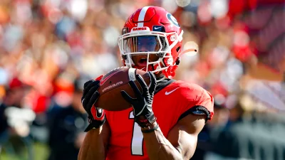 Focused College Football Player Securing Crucial Pass in Vibrant Red Uniform image