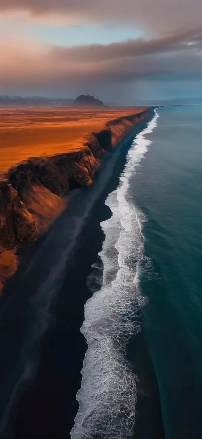 Breathtaking Aerial View of Black Sand Beach with Crashing Waves and Rugged Cliffs at Sunset image