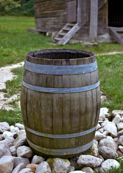 Rustic Wooden Barrel in Rural Landscape with Old Building and Stones image