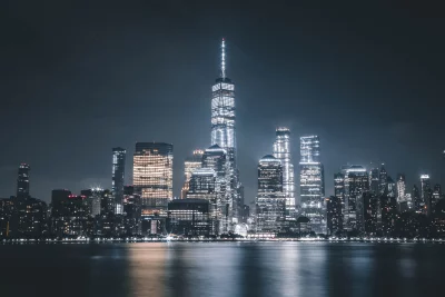 Manhattan Skyline at Night Featuring One World Trade Center Reflected on Water image