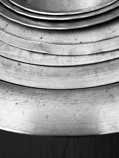 Detailed monochromatic texture of stacked vintage metal rings and curves creating abstract pattern image