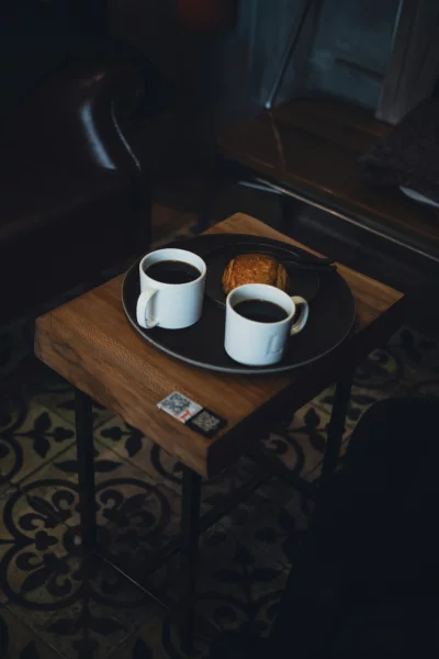 Two cups of coffee and a pastry on a wooden table