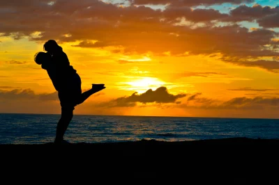 Romantic Couple Embracing in Silhouette Against a Vibrant Ocean Sunset image