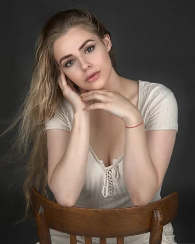 Serene Blonde Woman Portrait with Delicate Hand Pose on Wooden Chair image