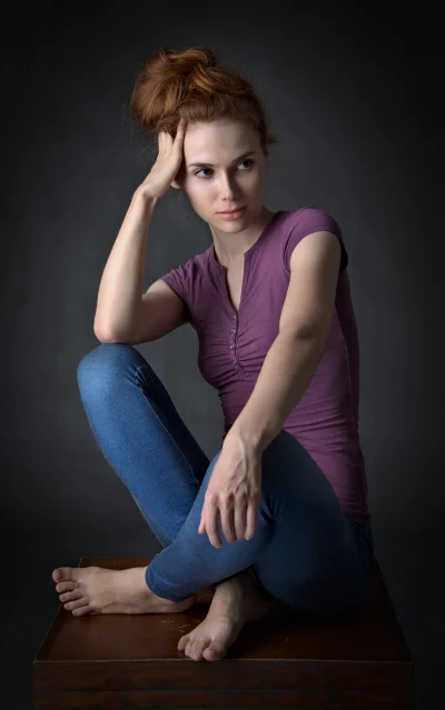 Pensive Young Woman with Red Hair and Blue Jeans Sitting Contemplatively image